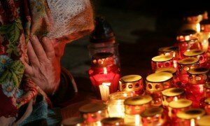 An elderly woman cries near the candles at a monument to Holodomor victims in central Kiev